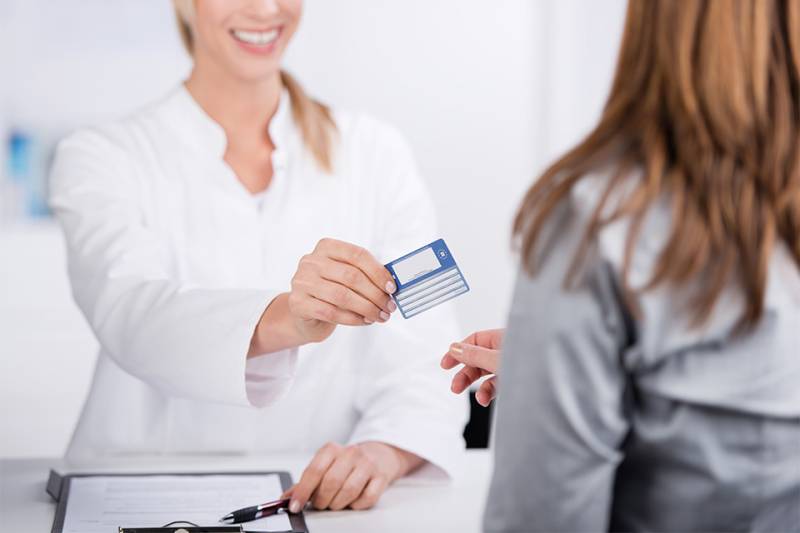 Patientin und Arzthelferin mit Versicherungskarte 